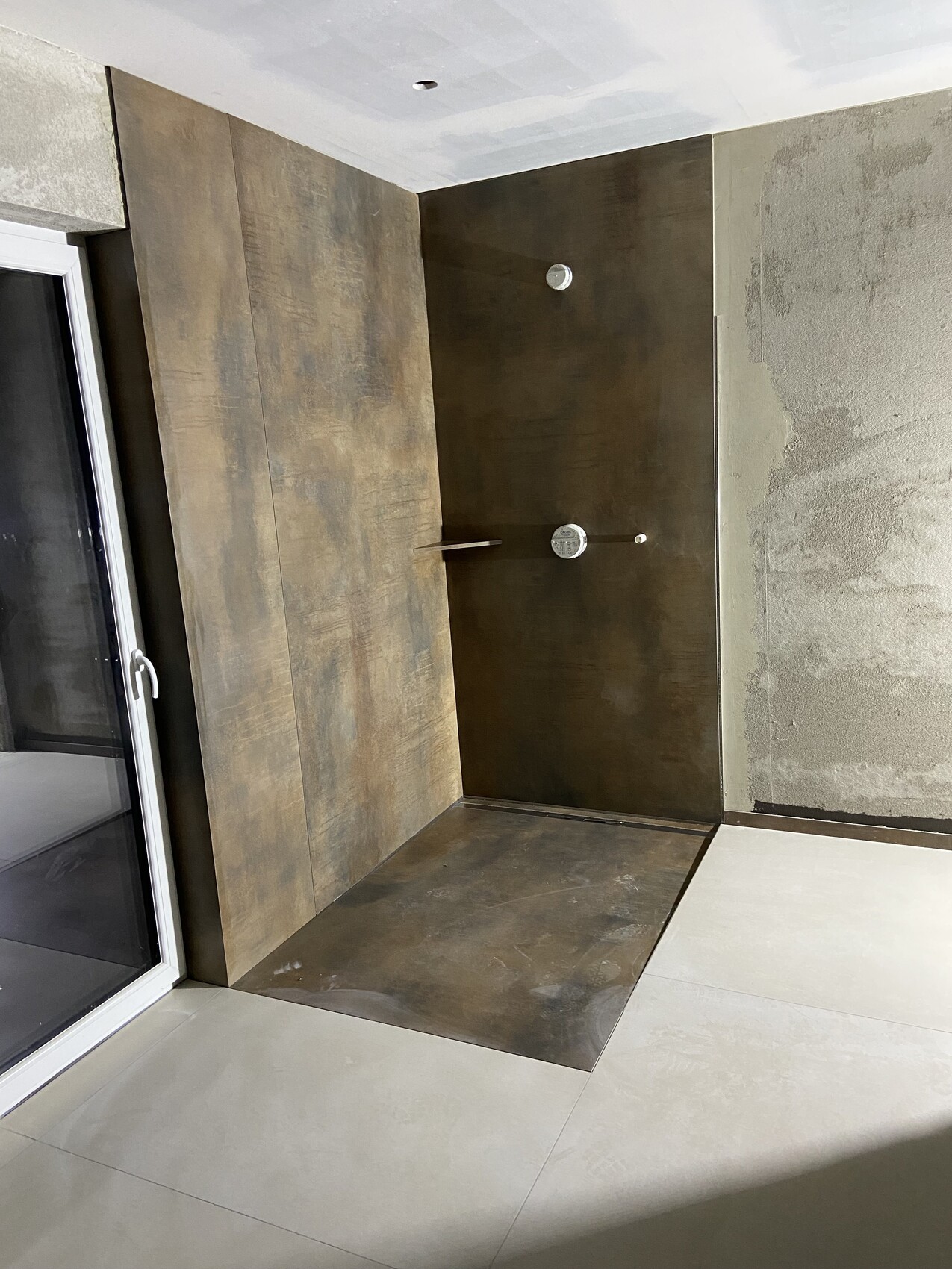 Dunkles Badezimmer mit Dusche, braune Wand- und Bodenverkleidung, moderne Fliesen