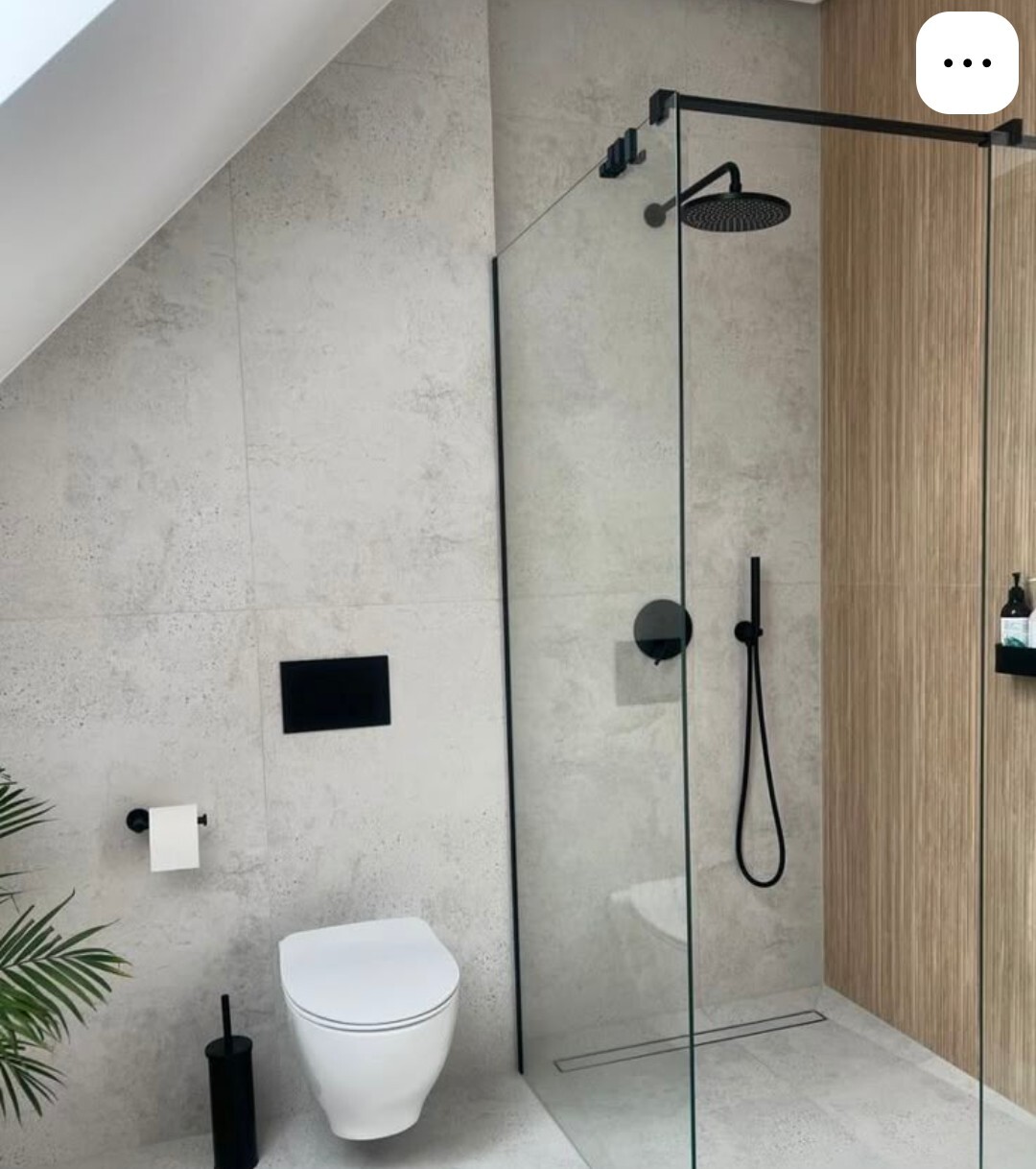 Modernes Badezimmer mit Glasdusche, grauen Betonfliesen, schwarze Armaturen, Toilette und Holzwand.