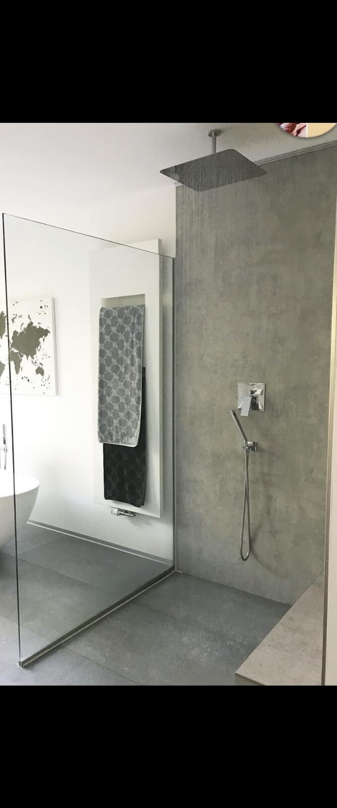 Großes modernes Badezimmer mit begehbarer Dusche, grauer Betonwand und Glasabtrennung