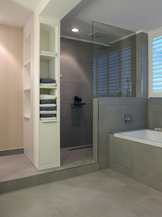 Modernes Badezimmer mit Dusche, Badewanne, Glasabtrennung und Handtuchregal.