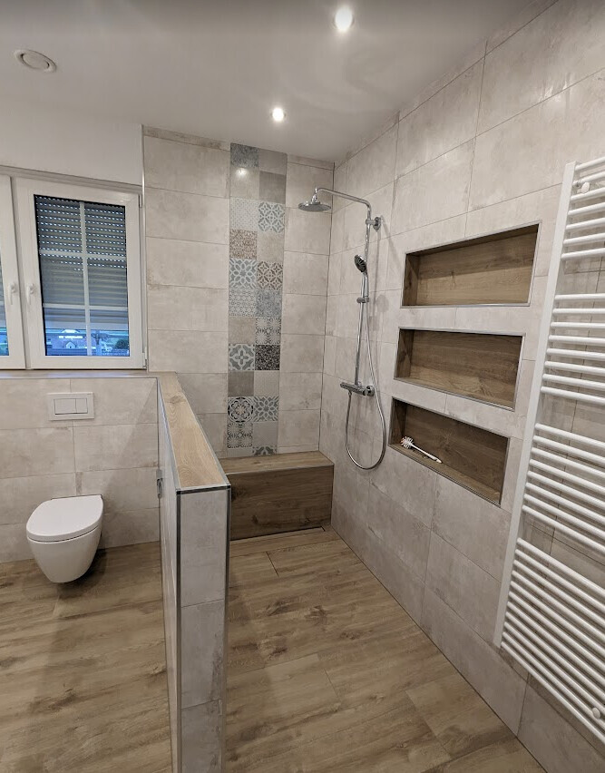 Modernes Badezimmer: Dusche mit Sitzbank, Wandnischen, Toilette, Fenster und Handtuchheizung.