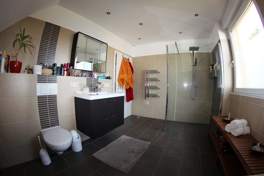 Modernes Badezimmer mit schwarzer Waschtisch-Konsole, Spiegel, Toilette, Glasdusche und Handtüchern.