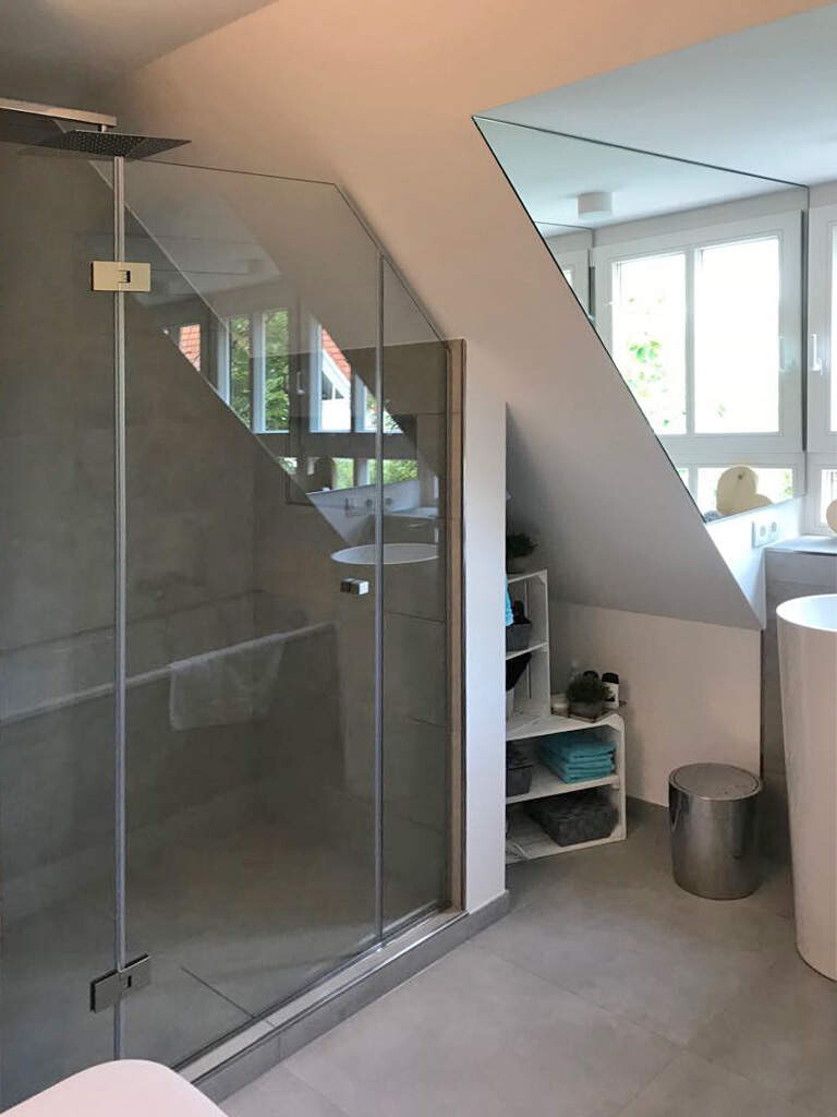 Modernes Badezimmer mit Glasdusche, schräger Decke, Fenster und Regal mit Handtüchern.