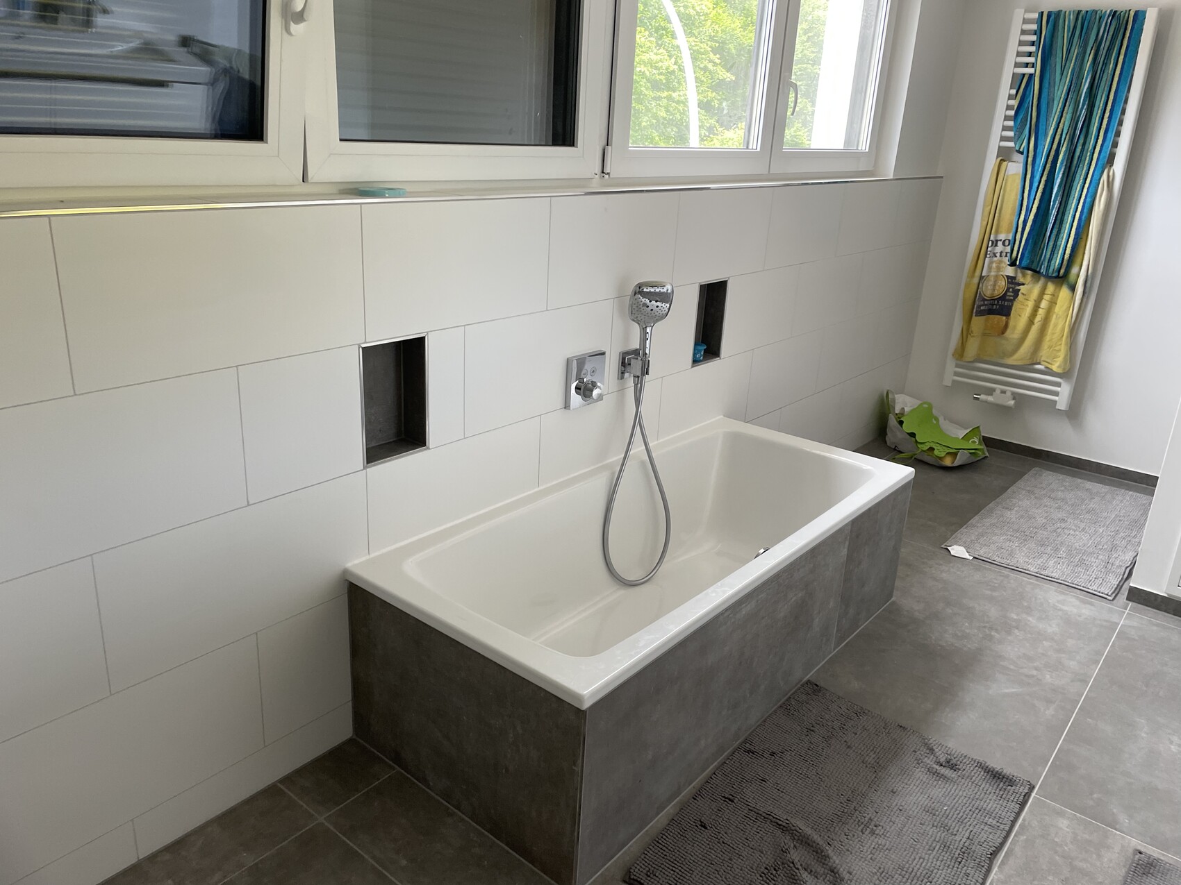 Moderne Badewanne mit Handbrause, weiße Fliesen, zwei Wandnischen, Handtuchheizung