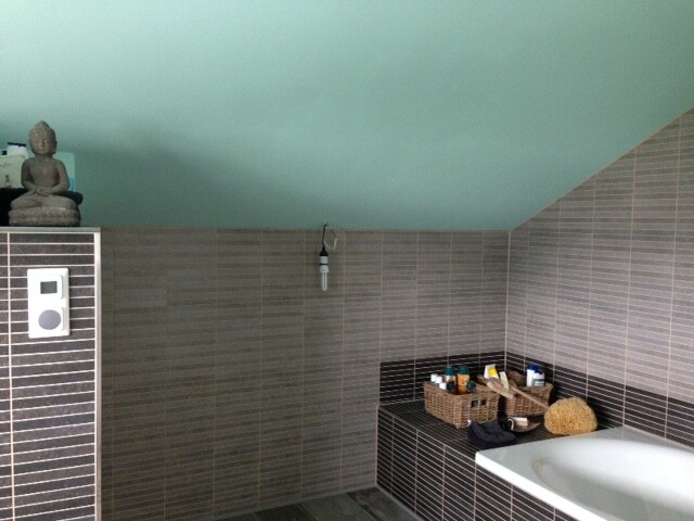 Modernes Badezimmer mit Badewanne, Fliesen und Buddha-Deko an der Wand