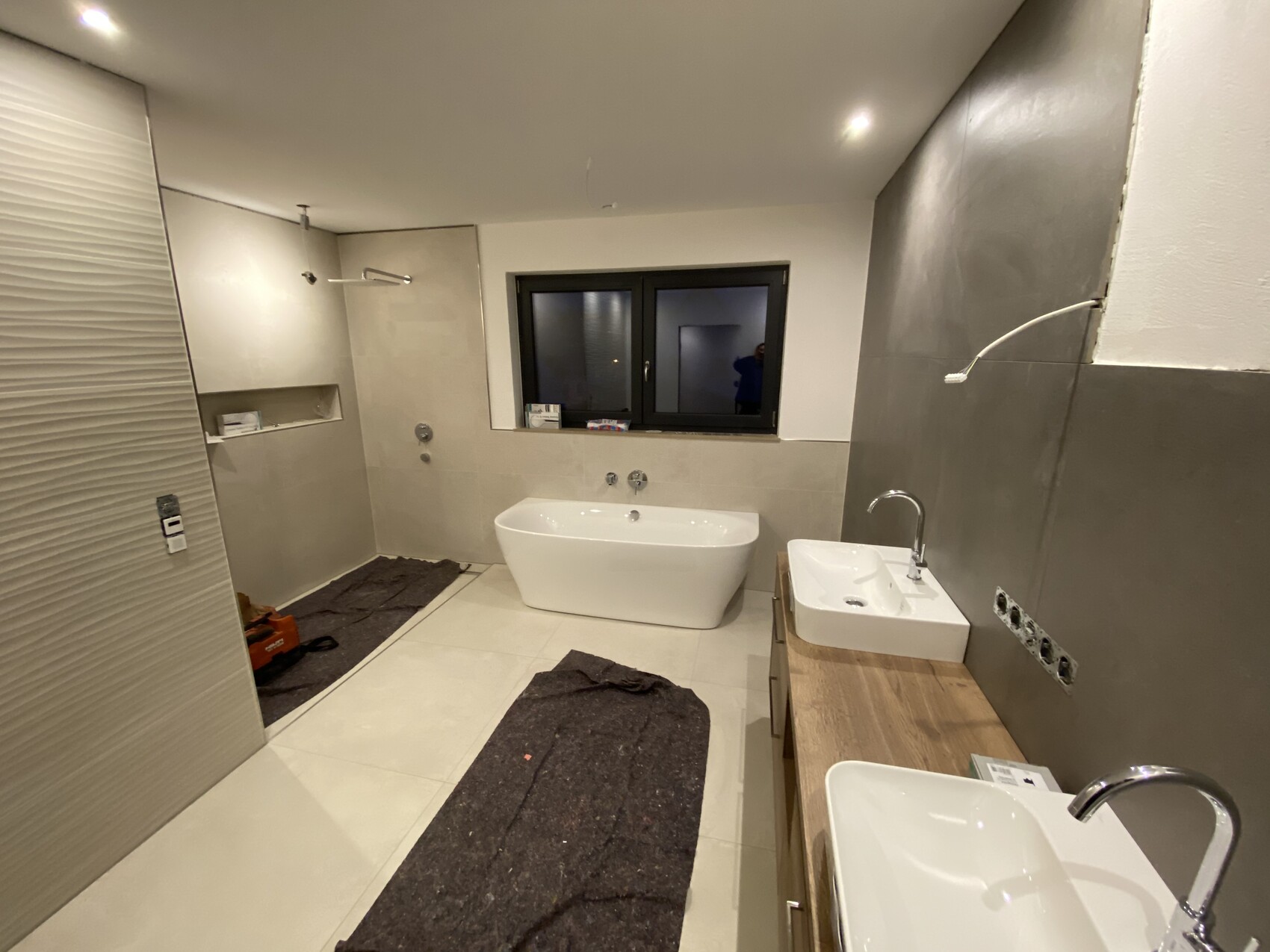 Modernes Badezimmer im Bau: freistehende Badewanne, Doppelwaschbecken, Dusche, Fenster.