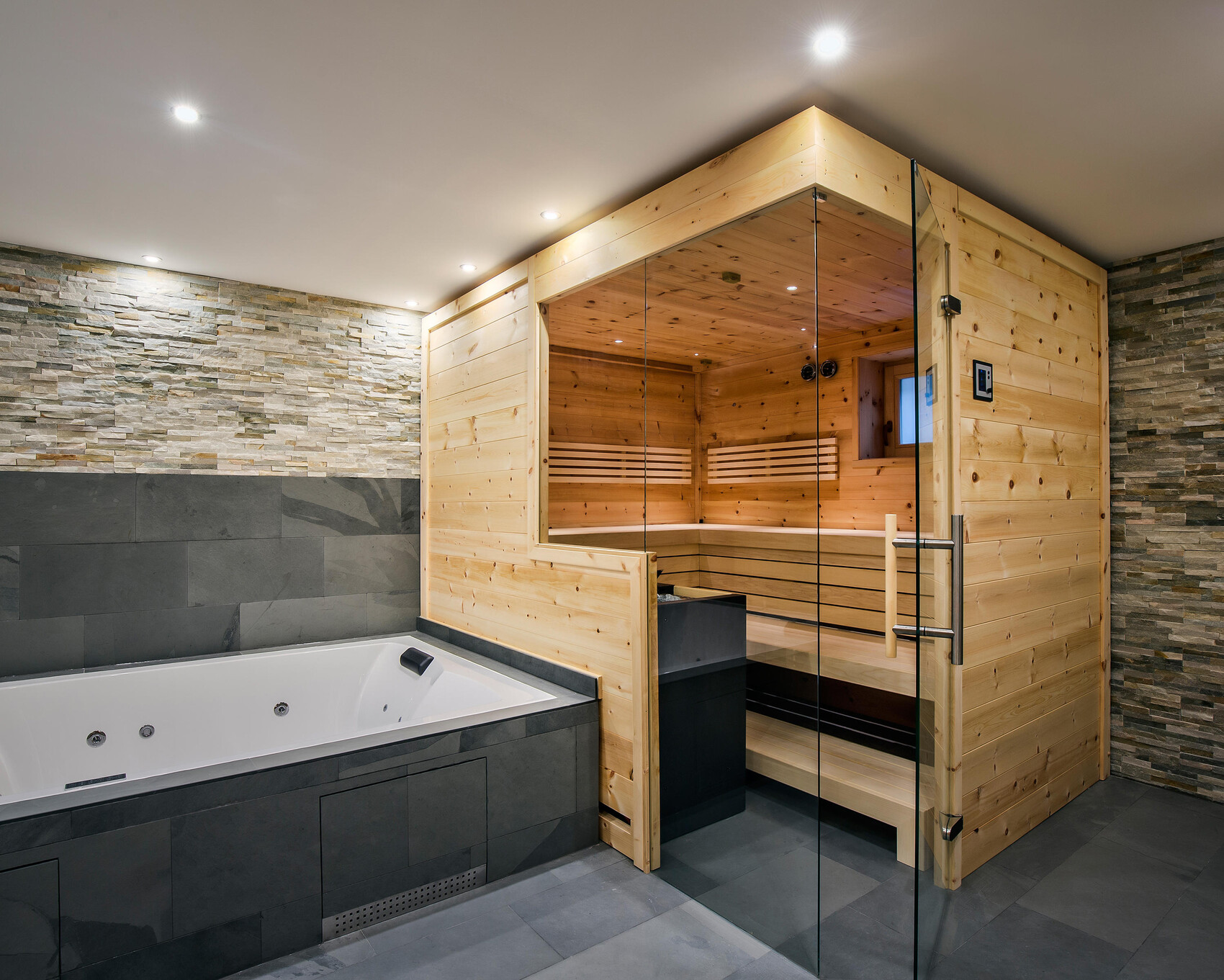 Große Badewanne neben einer Holzsauna mit Glasfront in einer modernen Wellness-Oase.