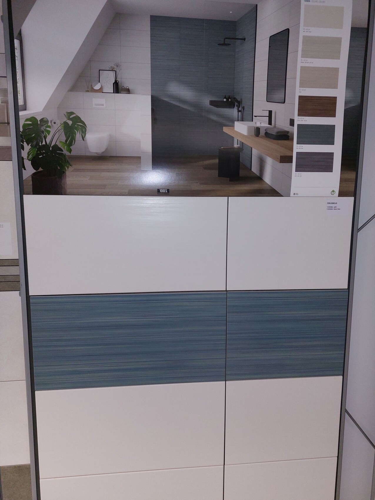 Modernes Badezimmer-Showroom mit blauen Fliesen, Holzboden und weissen Schränken