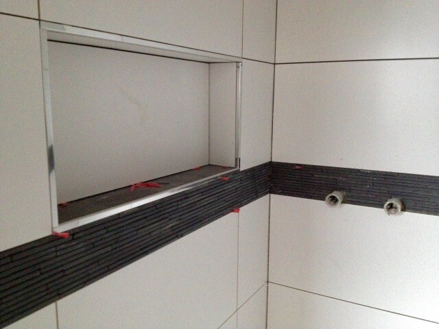 Weißes Badezimmer mit dunkler Fliesenleiste, Wandnische und Rohranschlüssen