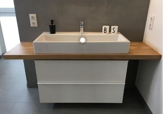 Waschtisch mit weißem rechteckigem Becken auf Holzplatte, Seifenspender und Buchstaben B S.