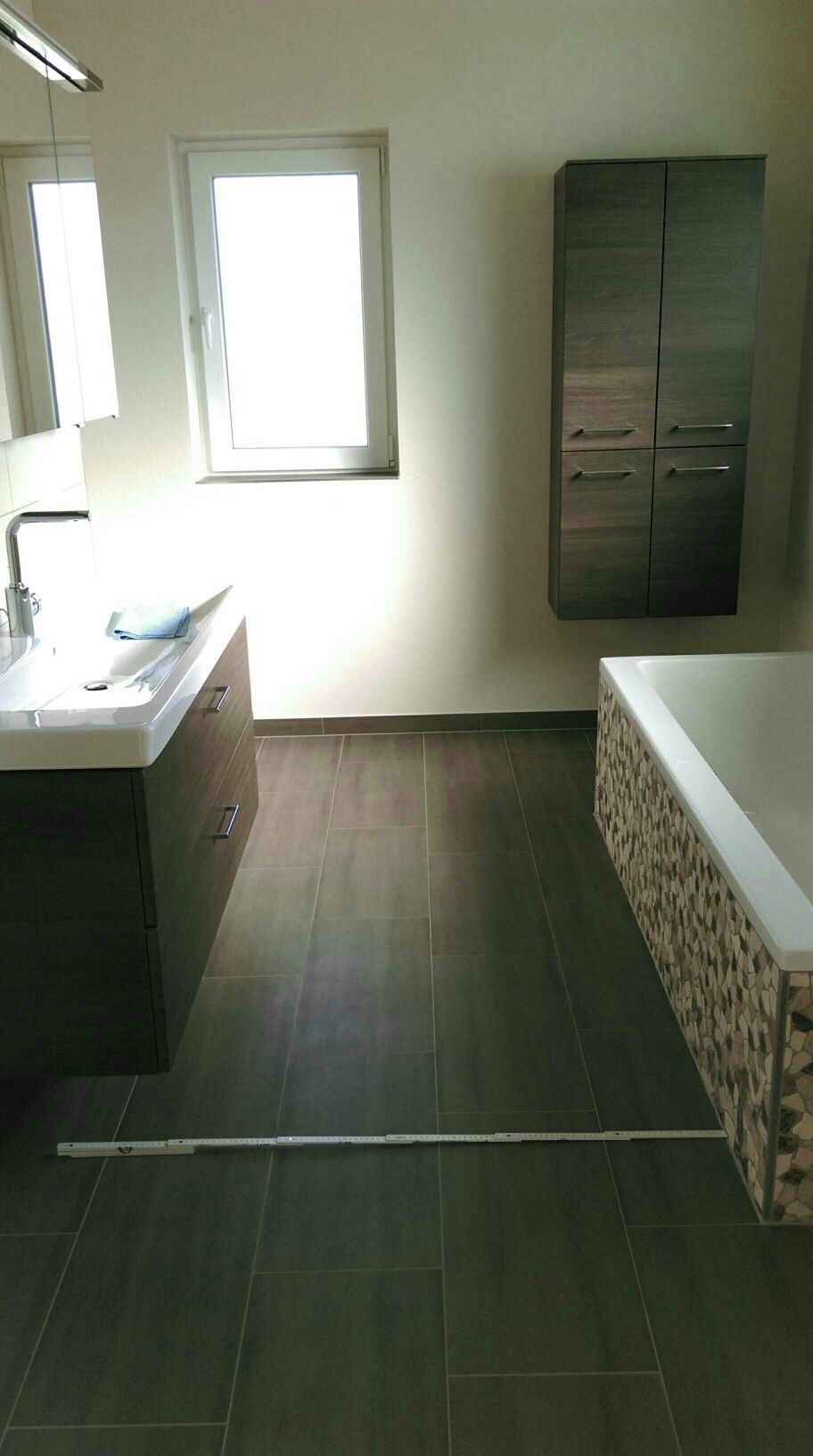 modernes-bad-waschtisch-schrank-badewanne-fliesen-dunkle-bodenfliesen.jpg