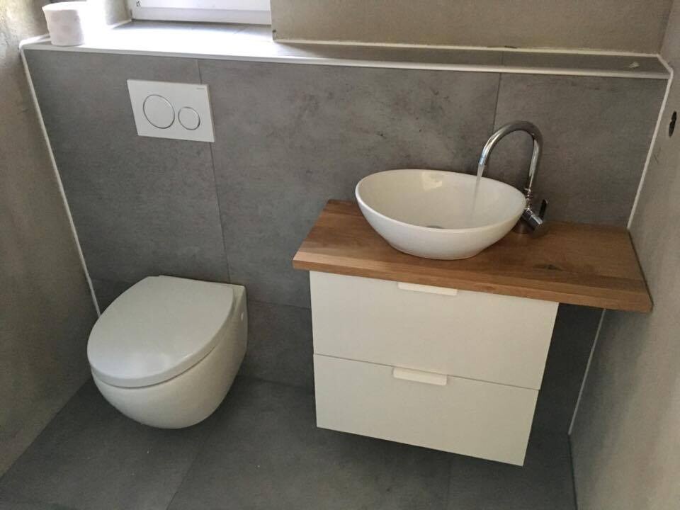 Moderne kleine Toilette mit Wandspülkasten, runder Keramikwaschbecken auf Holzplatte und Unterschrank