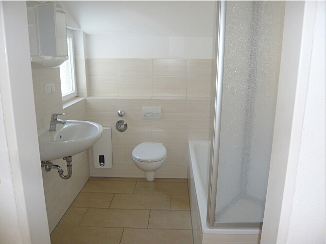 Kleines Badezimmer mit Waschbecken links, Wand-WC in Mitte, Badewanne und Duschkabine rechts.