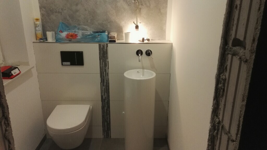 Badezimmer Renovierung: Toilette, freistehendes Waschbecken, Wandarmaturen, Utensilien auf Ablage.
