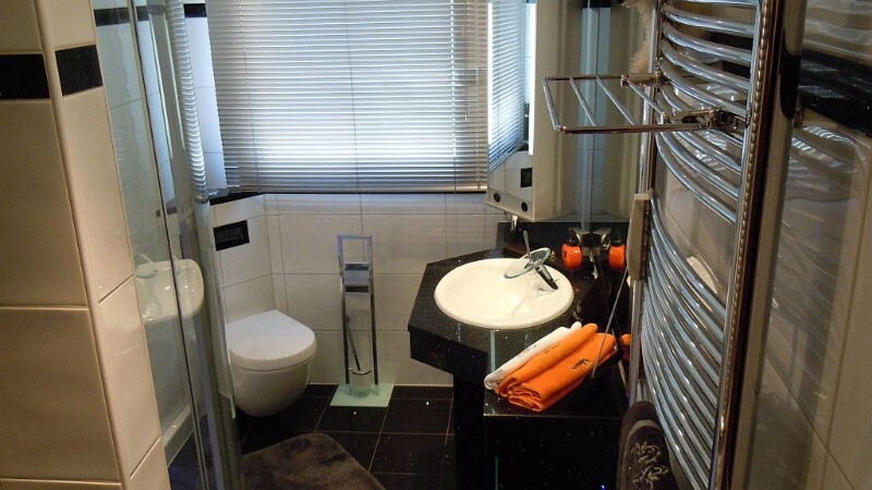 Kleines Badezimmer mit Waschbecken, Toilette, Dusche und Handtuchheizkörper
