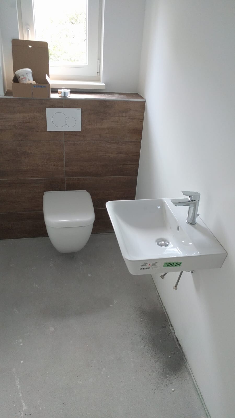 Modernes Badezimmer: wandhängende Toilette, rechteckiges Waschbecken, Holzverkleidung und Fenster.