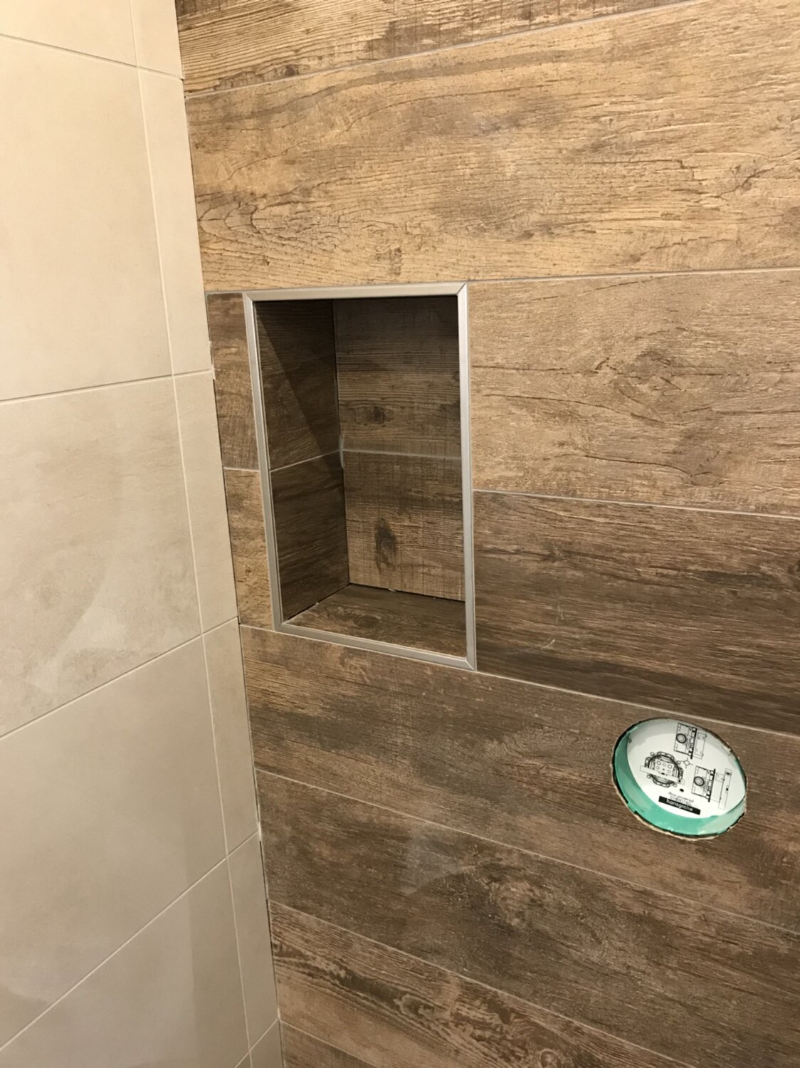 Badwand mit Holzoptikfliesen, rechteckige Nische mit Metallrahmen und runder Ausschnitt