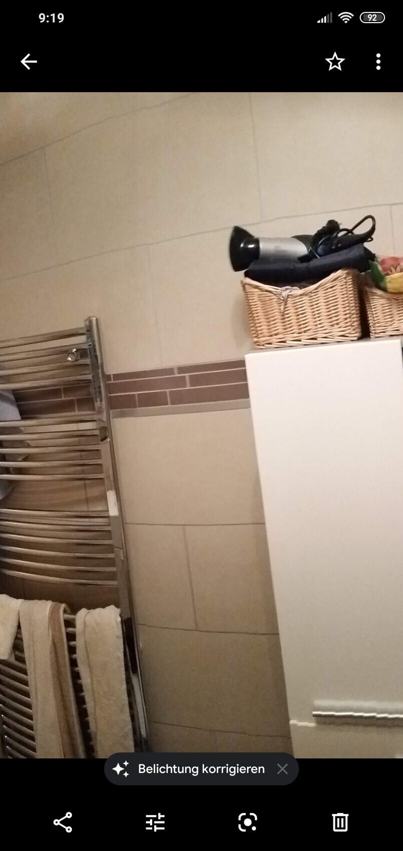 Badezimmer: Handtuchheizkörper links, weißer Schrank rechts, Korb mit Haartrockner.
