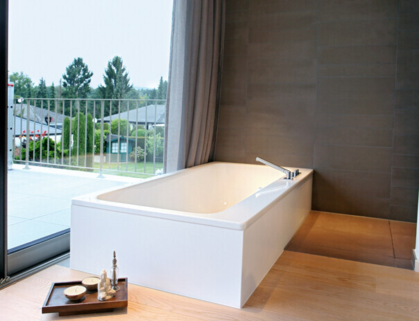 Modernes Badezimmer mit rechteckiger Badewanne, groessem Fenster und Terrassenzugang.