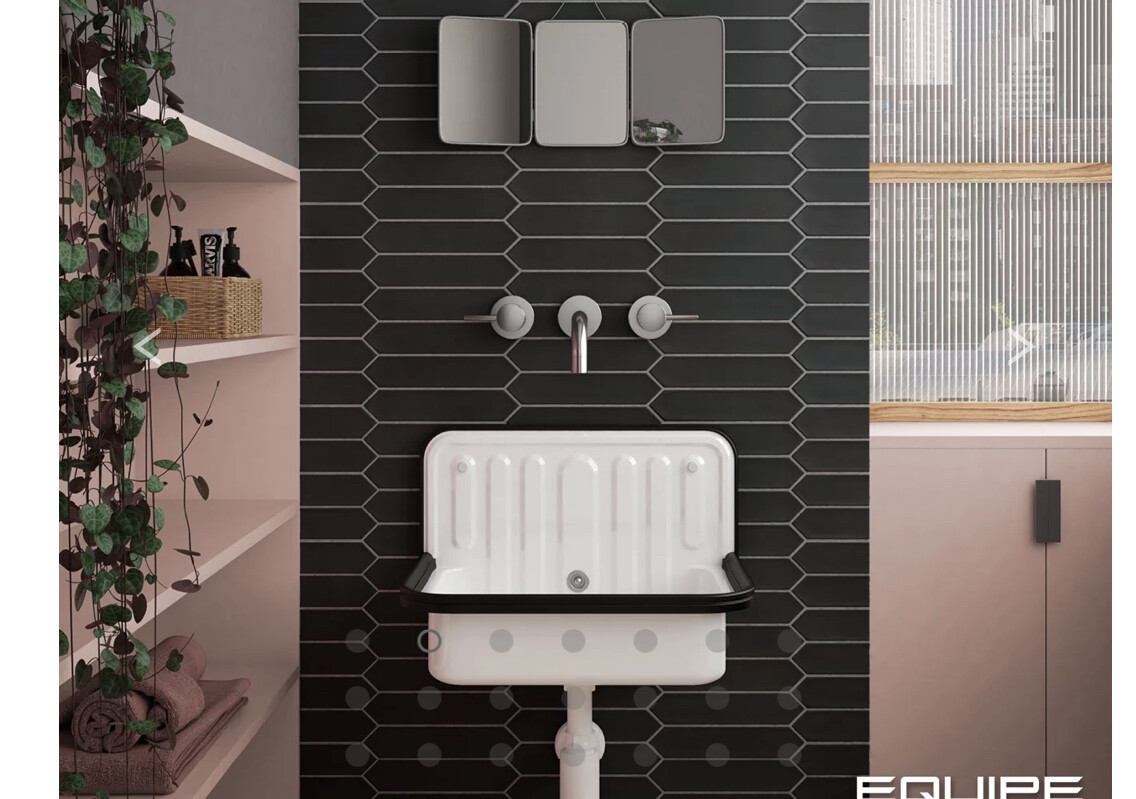 Kleines weißes Waschbecken vor schwarzer Hexagonfliesen-Wand, Armatur, links Pflanzregal.
