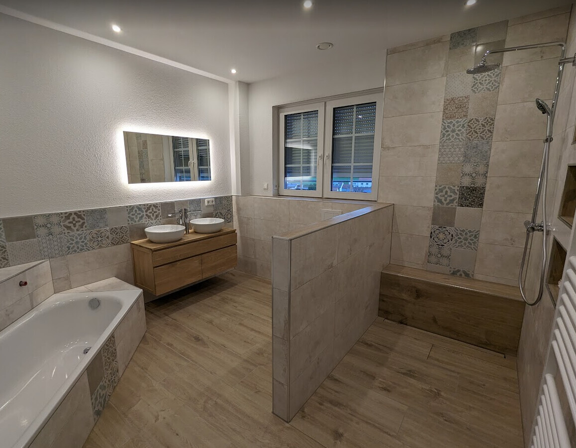 Modernes Badezimmer: Wanne links, Doppelwaschbecken auf Holzunterschrank, beleuchteter Spiegel.