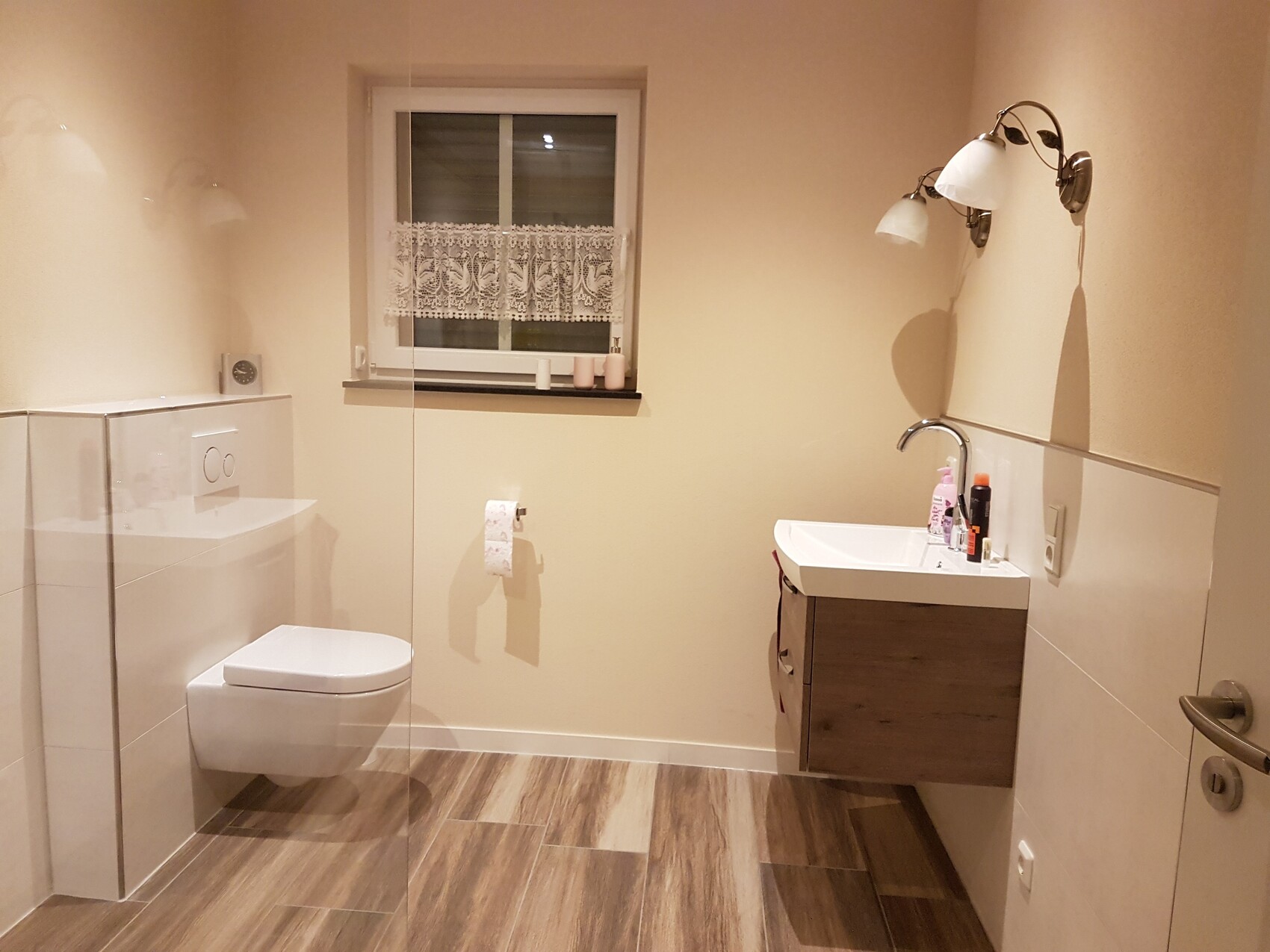 Modernes Badezimmer mit Toilette, Waschbecken, Fenster und Holzoptik-Boden