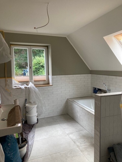 Renoviertes Badezimmer mit Badewanne, Fliesen und Fenster zum Garten