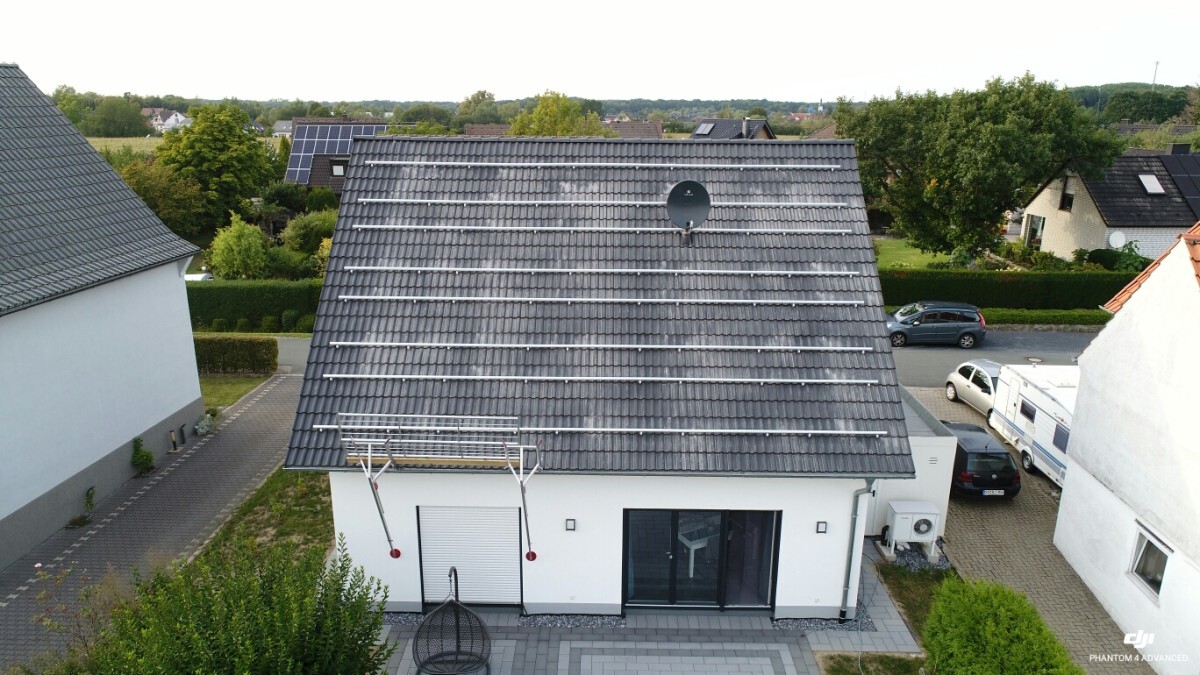 Drohnenbild eines Einfamilienhauses mit grauem Ziegeldach, Montageschienen und Satellitenschüssel.