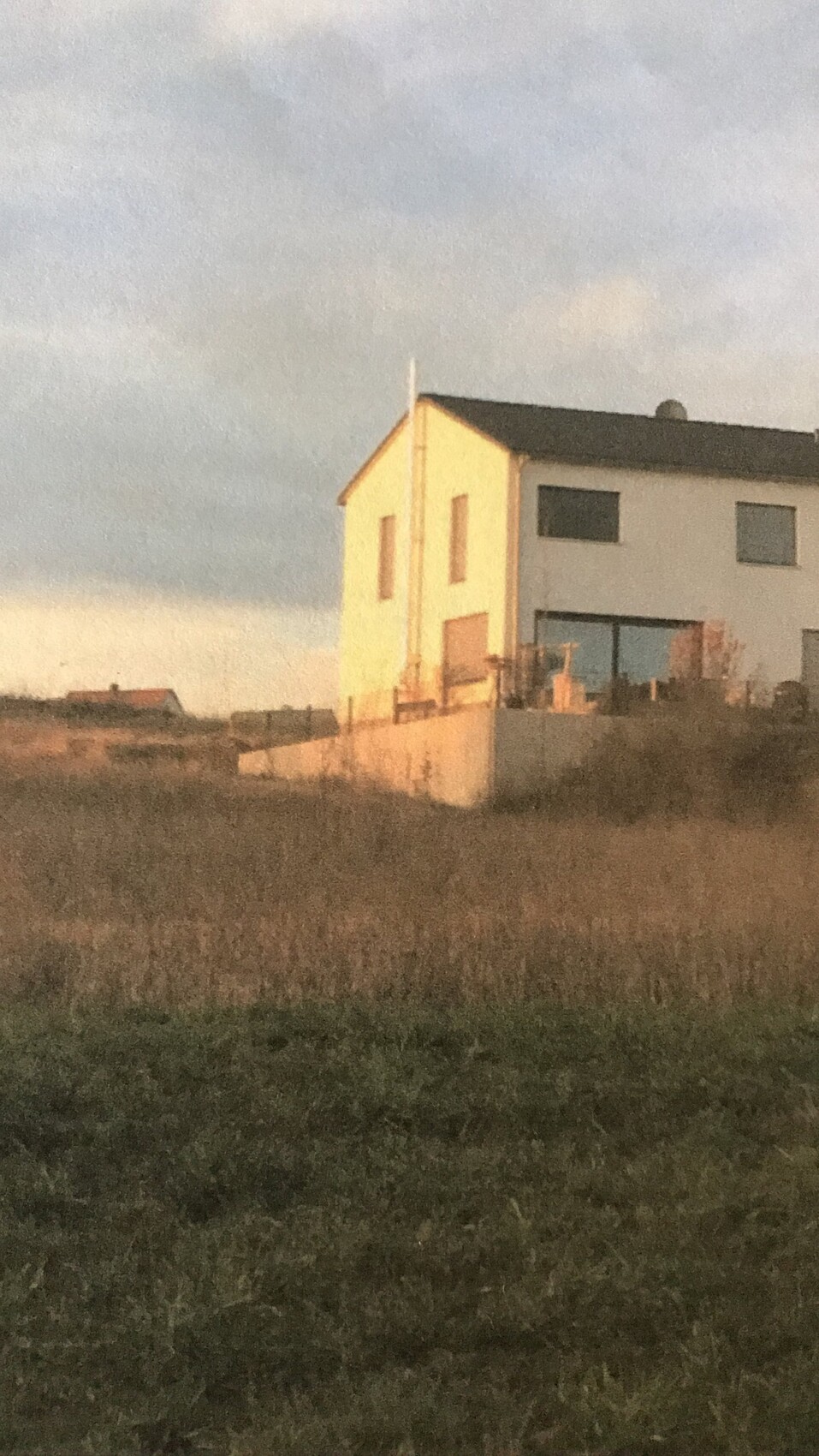 Moderne weiße Einfamilienhaus-Außenansicht auf offenem Grundstück bei Sonnenuntergang