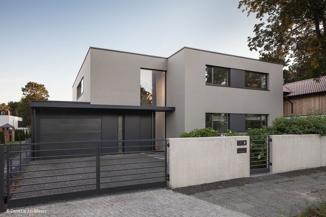Modernes, graues zweistöckiges Haus mit Garage, Metallzaun und Zufahrt