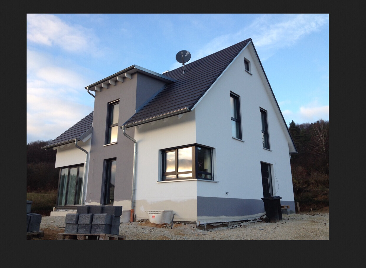 Neues Haus im Bau: weiße und graue Fassade, Dach, Fenster, Baustellenmaterialien