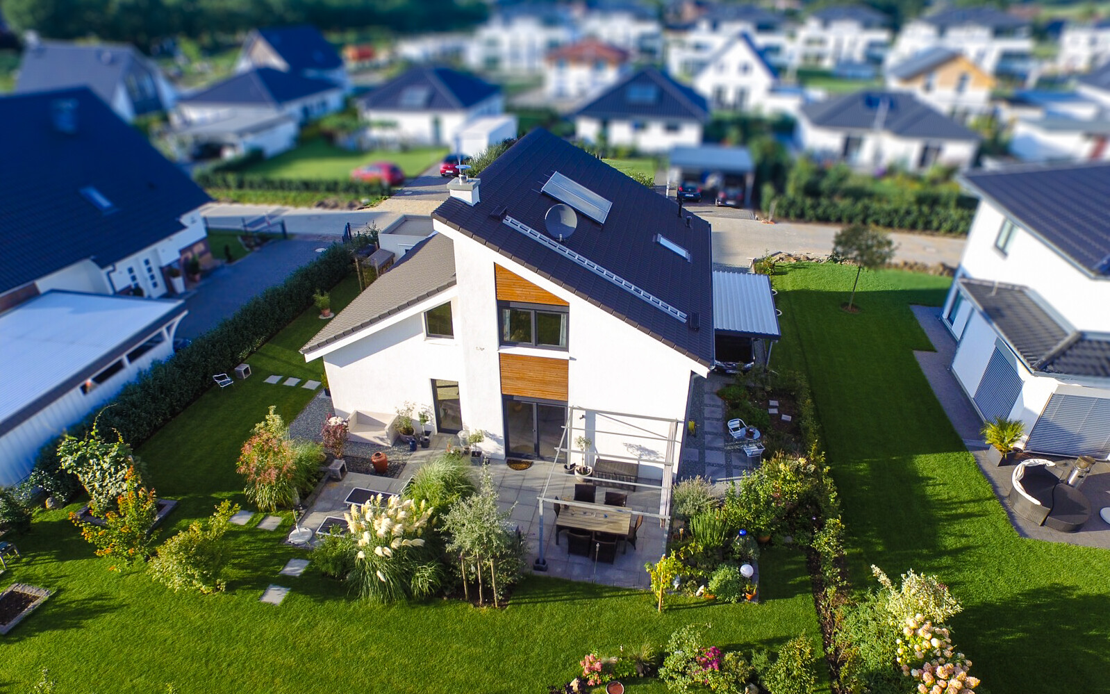 Luftaufnahme eines modernen Einfamilienhauses mit gepflegtem Garten und Terrasse.