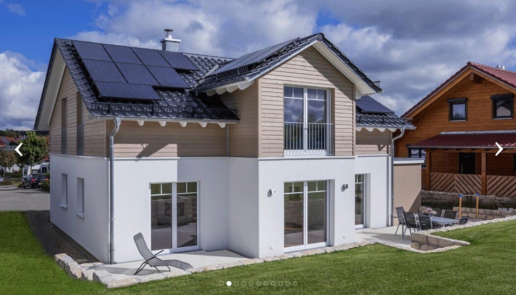 Moderne zweigeschossige Villa mit Solarzellen auf dem Dach, Terrasse und Garten.