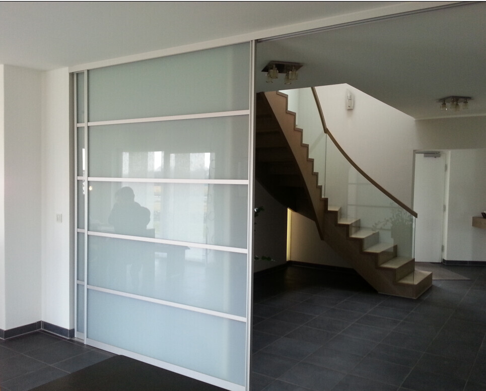 Moderne Innenansicht mit gläserner Trennwand links und geschwungener Treppe rechts.