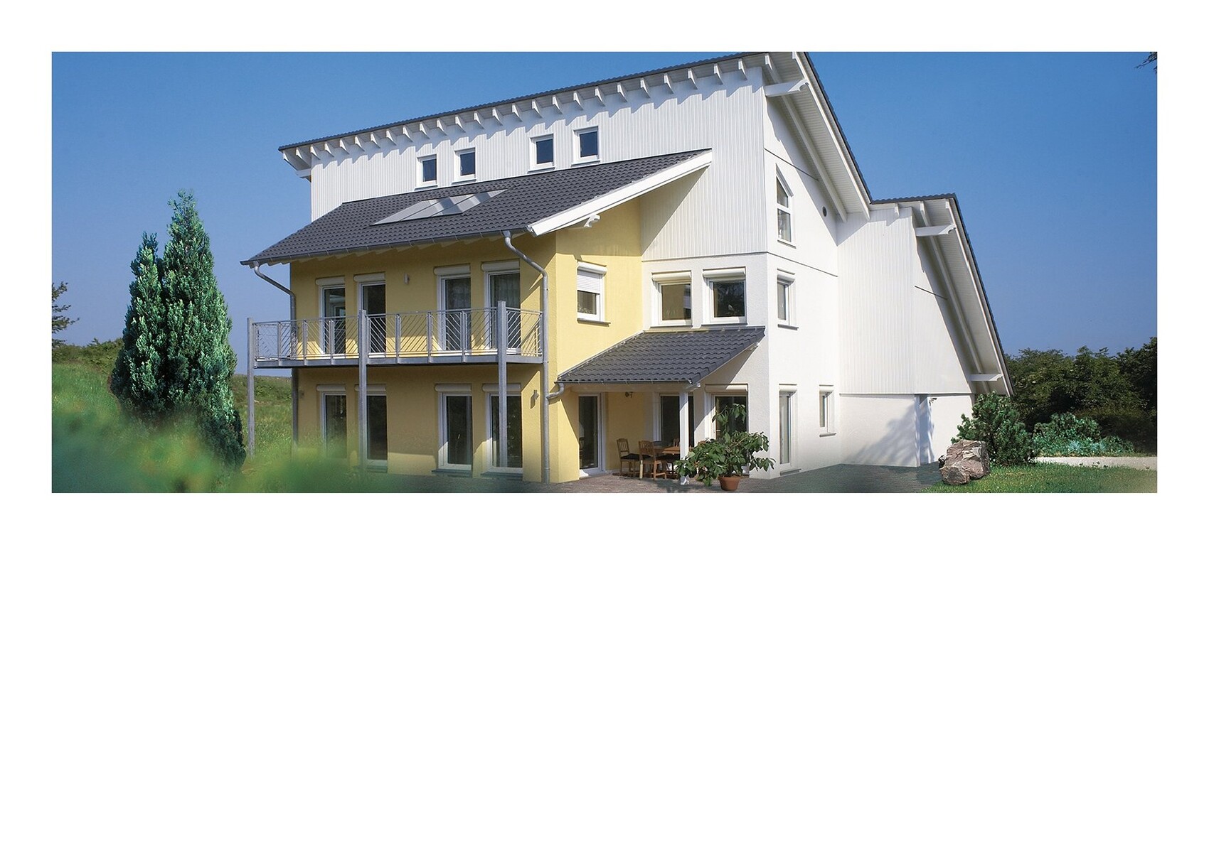 Modernes Haus mit gelber Fassade, Balkon, Terrasse und Garten unter blauem Himmel.