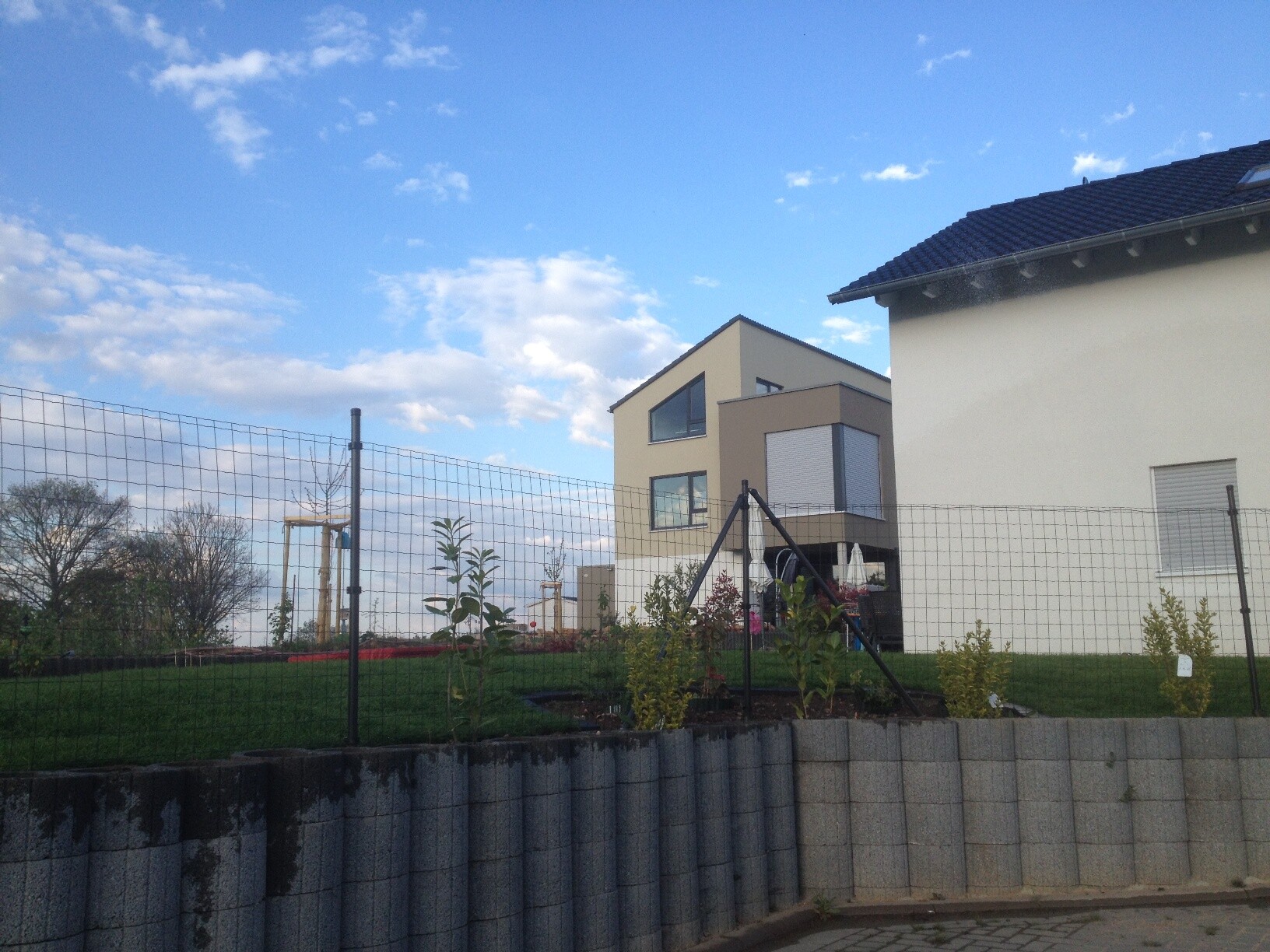Außenansicht eines modernen Einfamilienhauses mit Garten und Zaun