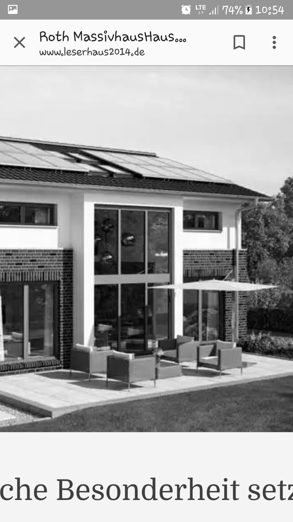 Modernes Einfamilienhaus mit großen Glasfronten, Terrassenmöbeln und Sonnenschirme