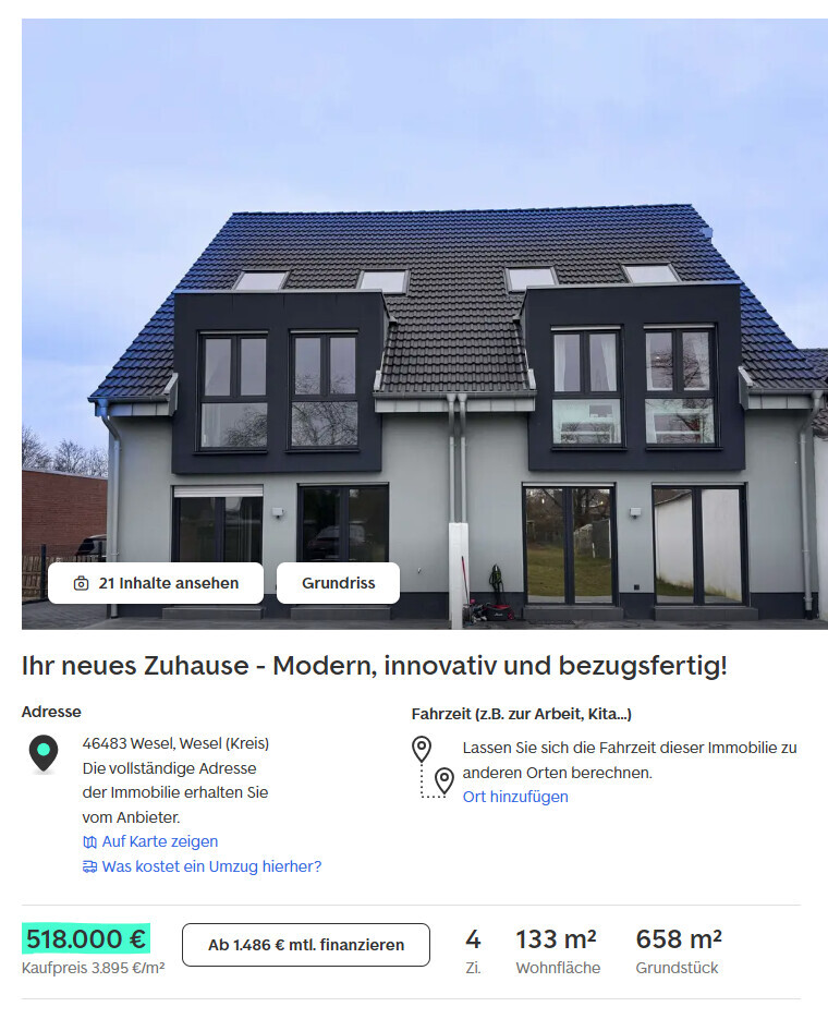 Modernes Doppelhaus mit dunkler Fassade, großen Fenstern und Dachflächenfenstern vor blauem Himmel.