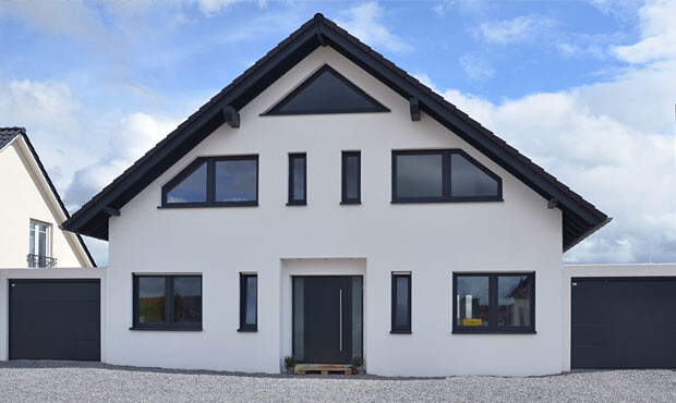 Modernes weißes Einfamilienhaus mit dunklem Satteldach, zwei Garagen und zentralem Eingang