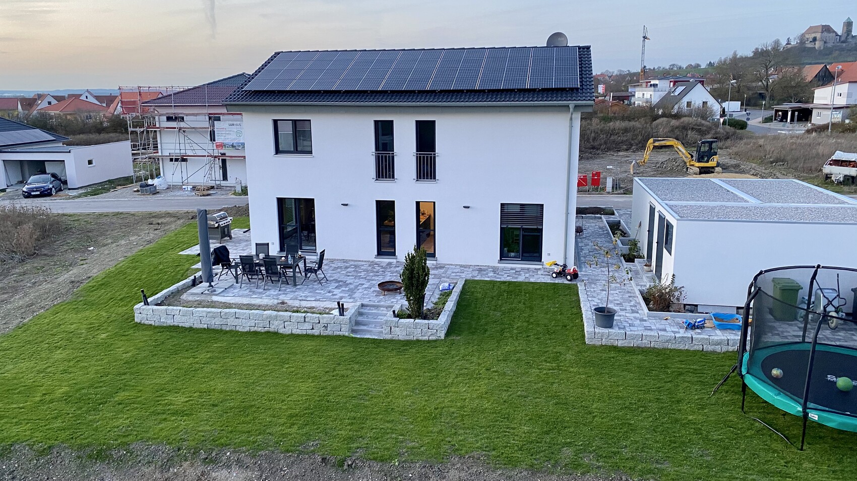 Modernes zweistöckiges Haus mit Solarpanel-Dach, Terrasse und Garten.