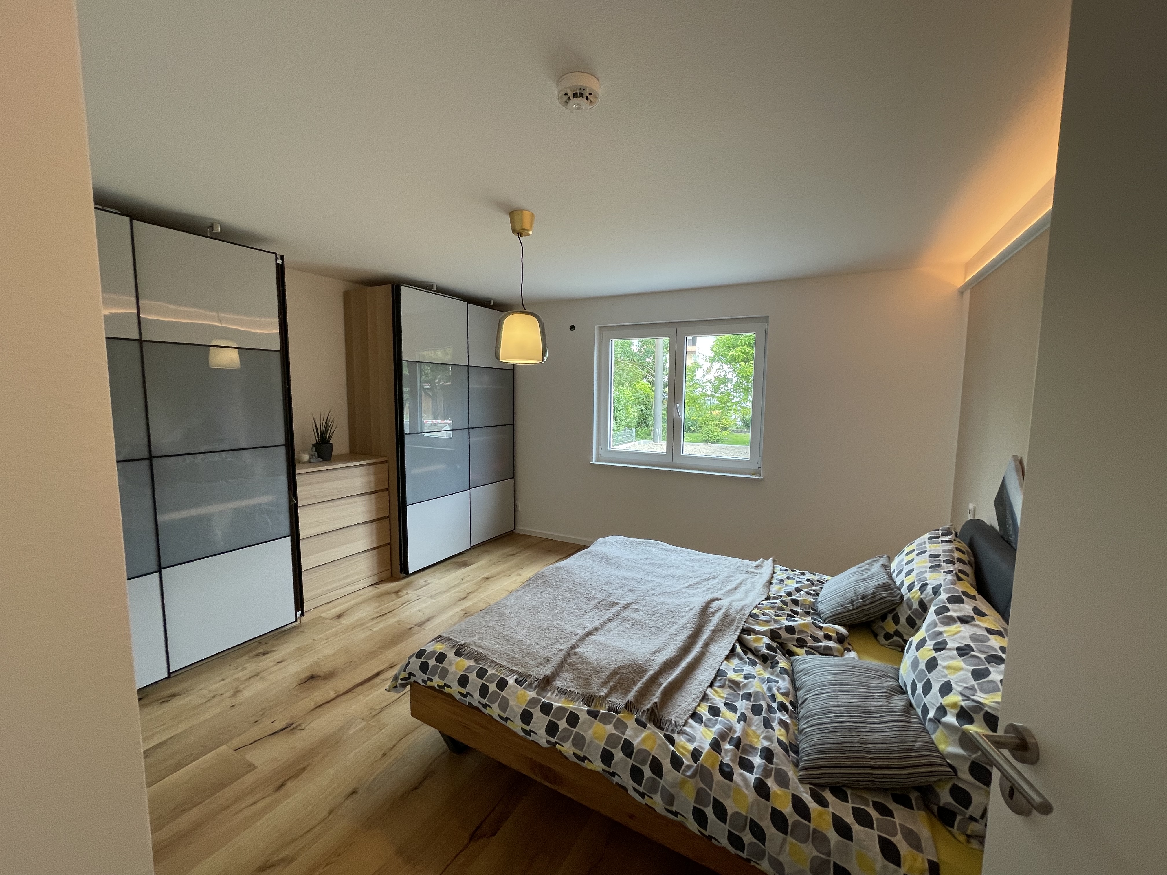 modernes-schlafzimmer-mit-holzboden-grosse-glas-fronten-bett.jpeg