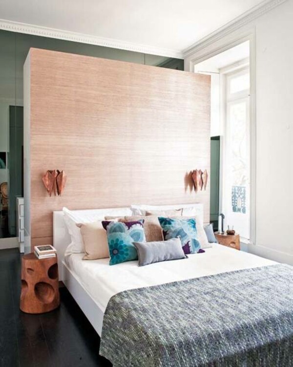 Modernes Schlafzimmer: großes Holz-Kopfteil, weißes Bett, bunte Kissen, runde Holznachttische.