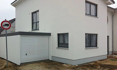Außenansicht eines modernen weißen Hauses mit Garage und Fenstern.