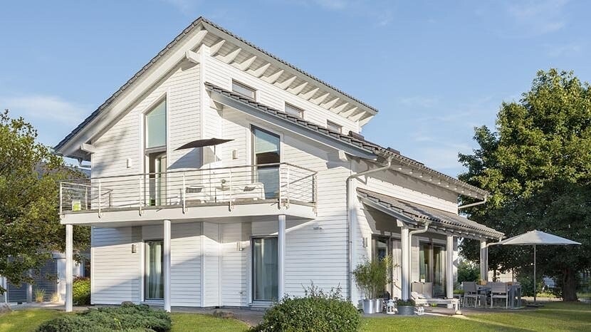 Weißes, modernes zweistöckiges Einfamilienhaus mit Balkon, Terrasse und Garten.