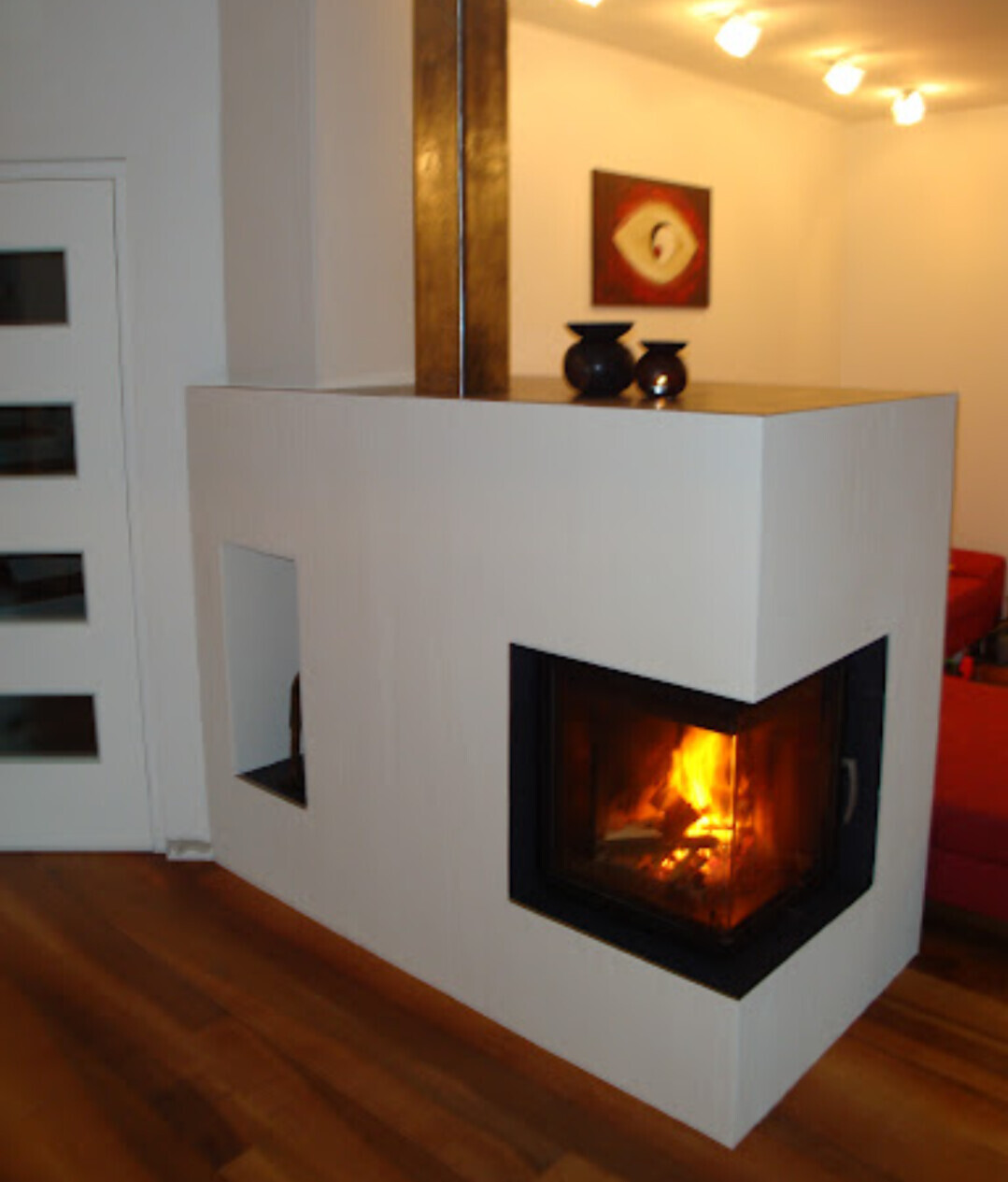 Moderner weißer Kamin mit brennendem Feuer in hellem Wohnzimmer.