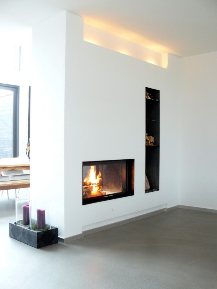 Moderne weiße Wohnwand mit eingebautem Kamin und vertikalem Regal.