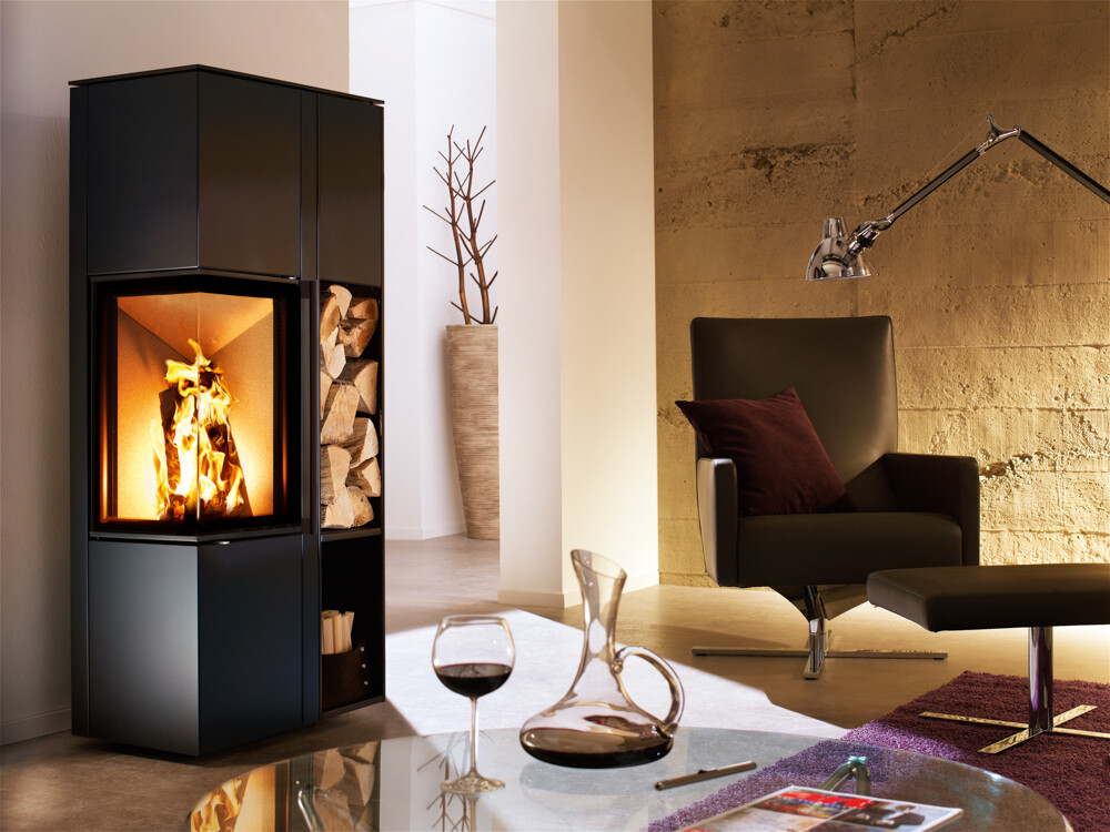 Modernes Wohnzimmer mit Kaminfeuer, schwarzer Ledersessel, Hocker und Glas-Tisch mit Wein