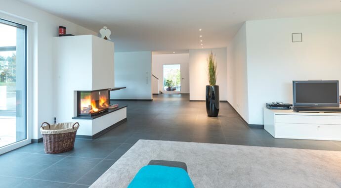 Offener moderner Wohnraum mit Kamin links, TV-Schrank rechts und großer Pflanzkübel