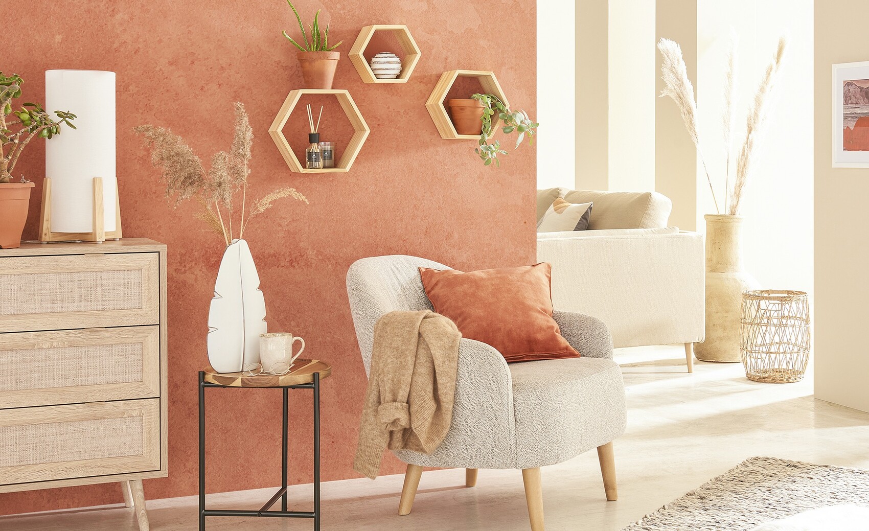 Wohnzimmer mit terrakotta Wand, grauem Sessel, orange Kissen, hexagonale Wandregale und Pflanzen.