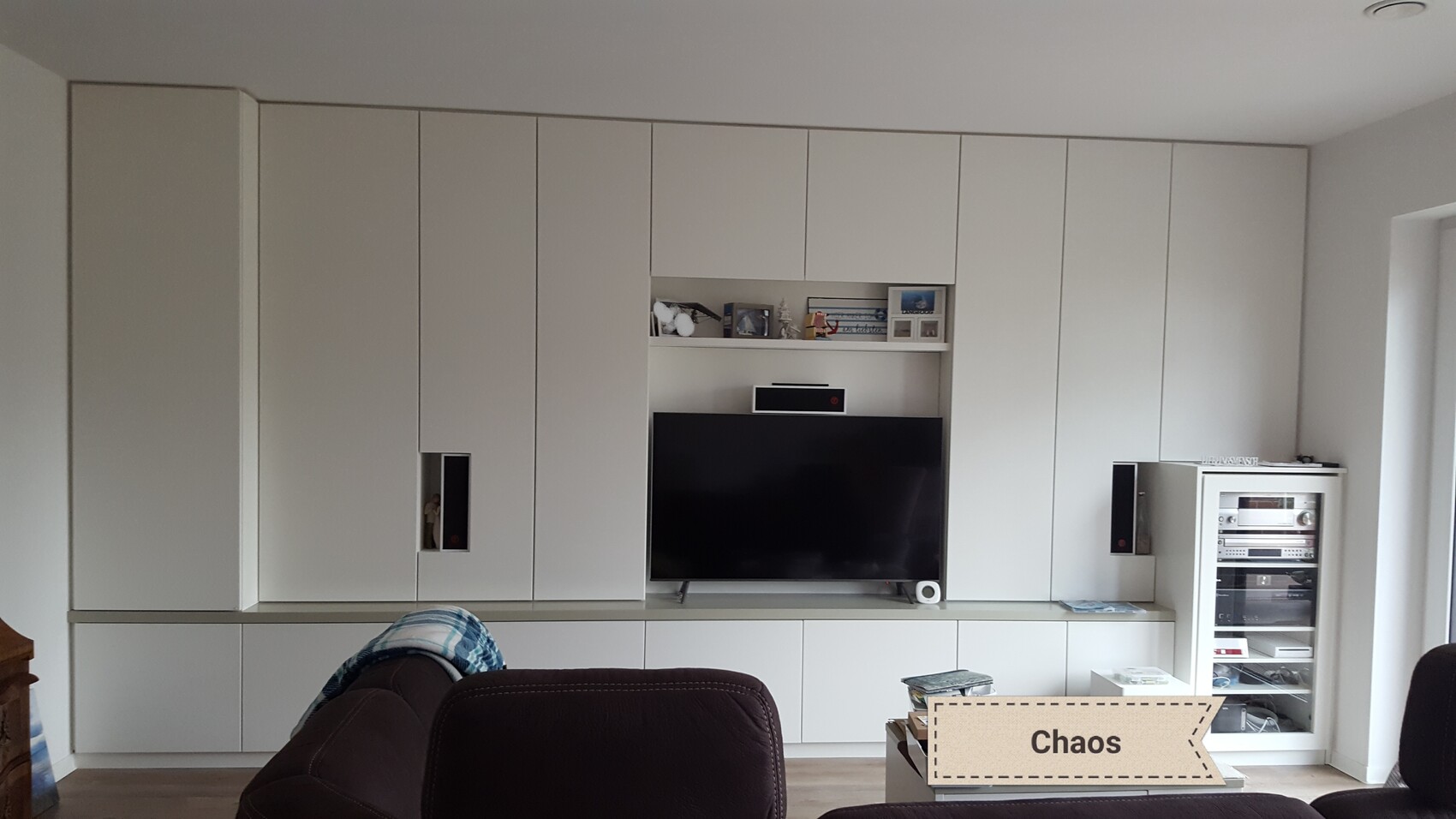 Helles Wohnzimmer mit weißen Einbauschränken, Fernseher und Medienwand